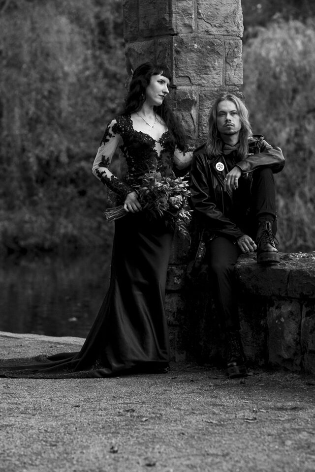 Gothic-Paar in Schwarz vor mittelalterlicher Kulisse – Metal Me zeigt, wie düster-romantisch eine Metal Hochzeit bei Hell Yes! Weddings sein kann