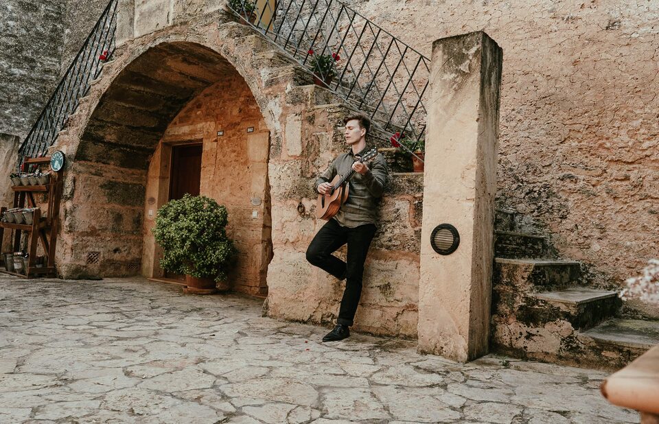 Rockiger Hochzeitssänger Nico Grund mit Gitarre vor rustikalem Torbogen