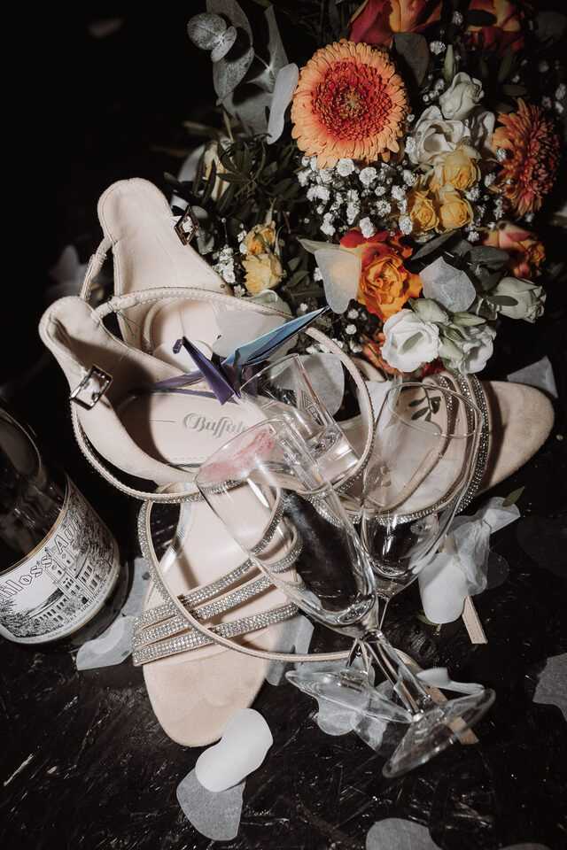 Hochzeitsfotografie von Patricia Bakker: Brautschuhe, Sektgläser und bunter Brautstrauß als Detailshot fürs Getting Ready.