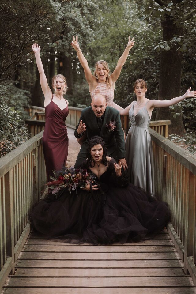Bridal Party auf der Holzbrücke mit Rock-Posen – Gruppenfoto für eine alternative Hochzeit, fotografiert von Patricia Bakker.