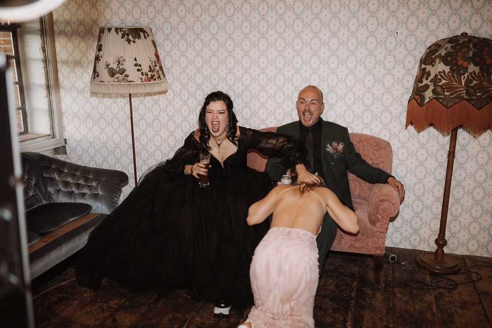 Brautpaar lacht sich auf dem Sofa weg – ungestellte Reportage-Momente, fotografiert von Patricia Bakker (alternativ heiraten).