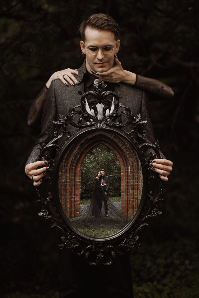 Hochzeitsfotografie von Patricia Bakker bei Hell Yes! Weddings: Gothic-Paarshooting mit Spiegelrahmen – Brautpaar im schwarzen Look in der Spiegelreflexion, das perfekte Foto einer alternativen Hochzeit.