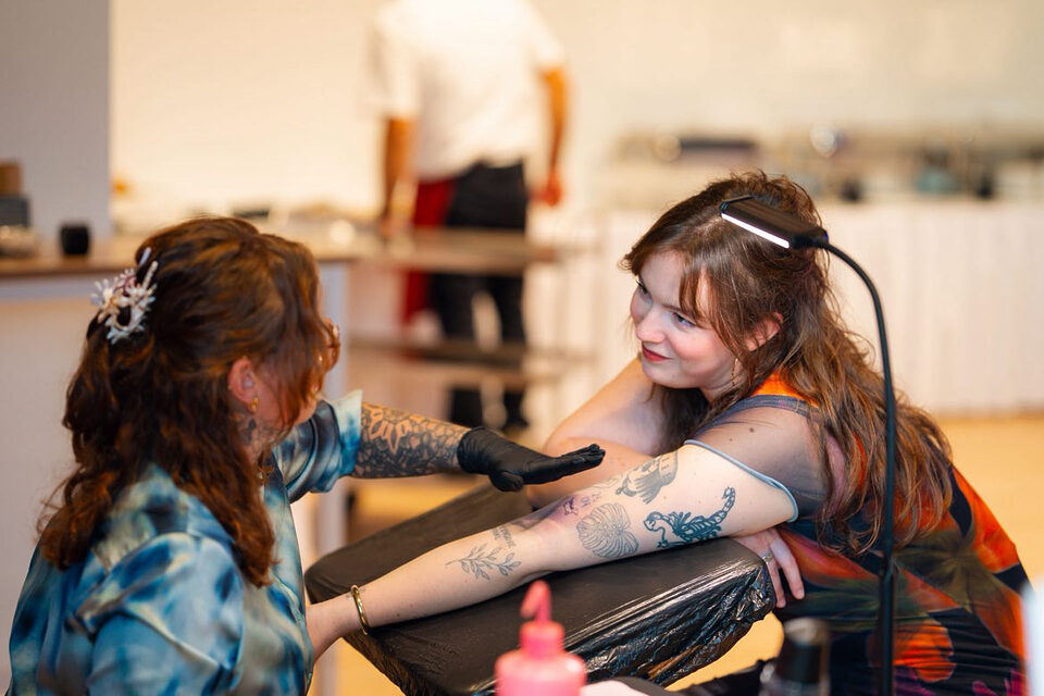Dannii von inkmoment spricht mit einem Hochzeitsgast an der mobilen Tattoo-Station.