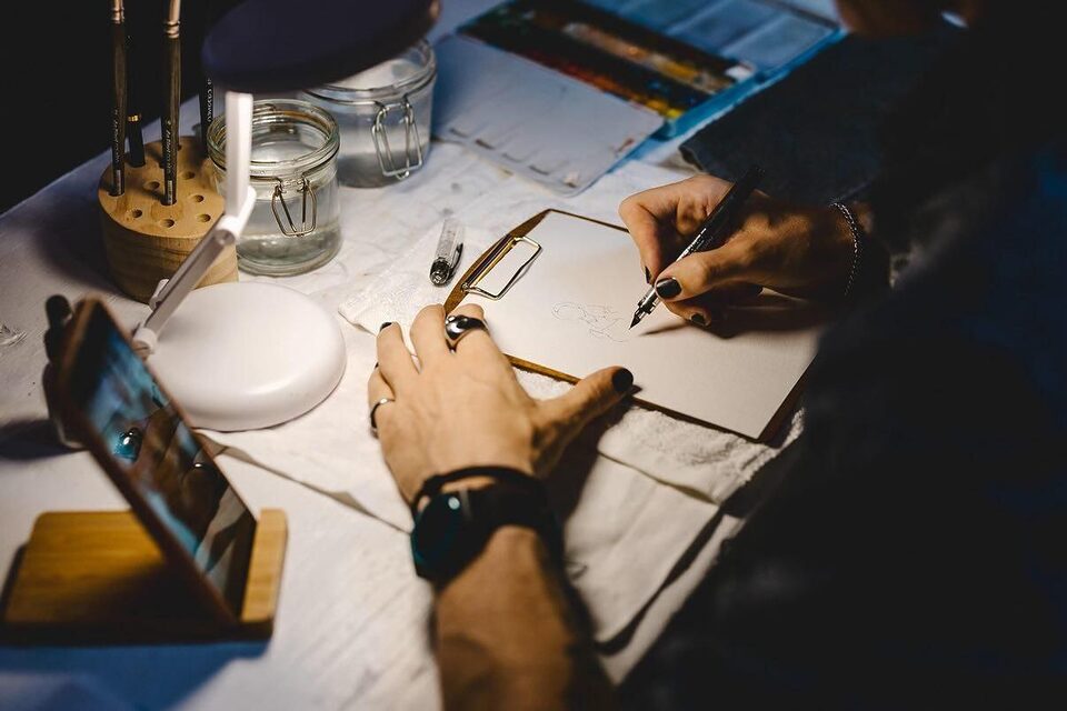 Hände eines Schnellzeichners beim Live Painting auf einer Hochzeit – Aquarell und Tusche in Arbeit.