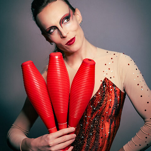 Verena Rau Entertainment mit roten Jonglierkeulen als Showact in rot glitzerndem Bühnenkostüm