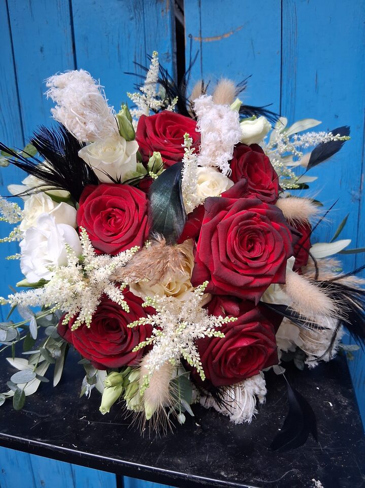 Brautstrauß aus dunkelroten und weißen Rosen mit schwarzen Federn, hellen Gräsern und Eukalyptus