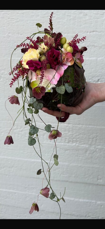Kompaktes florales Handstück in Rosa, Bordeaux und Creme mit Beeren und langen hängenden Ranken