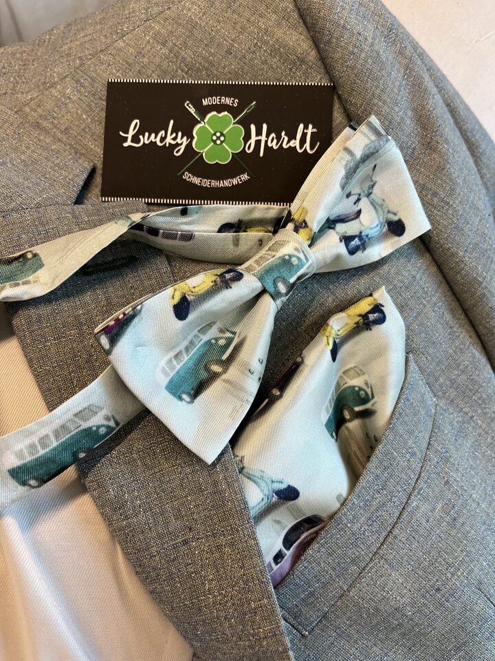Grauer Anzug mit bedruckter Fliege, Einstecktuch und Visitenkarte von Lucky Hardt