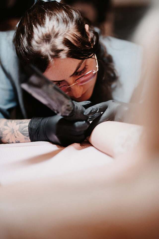 Dannii von ink moment sticht konzentriert ein feines Hochzeitstattoo.