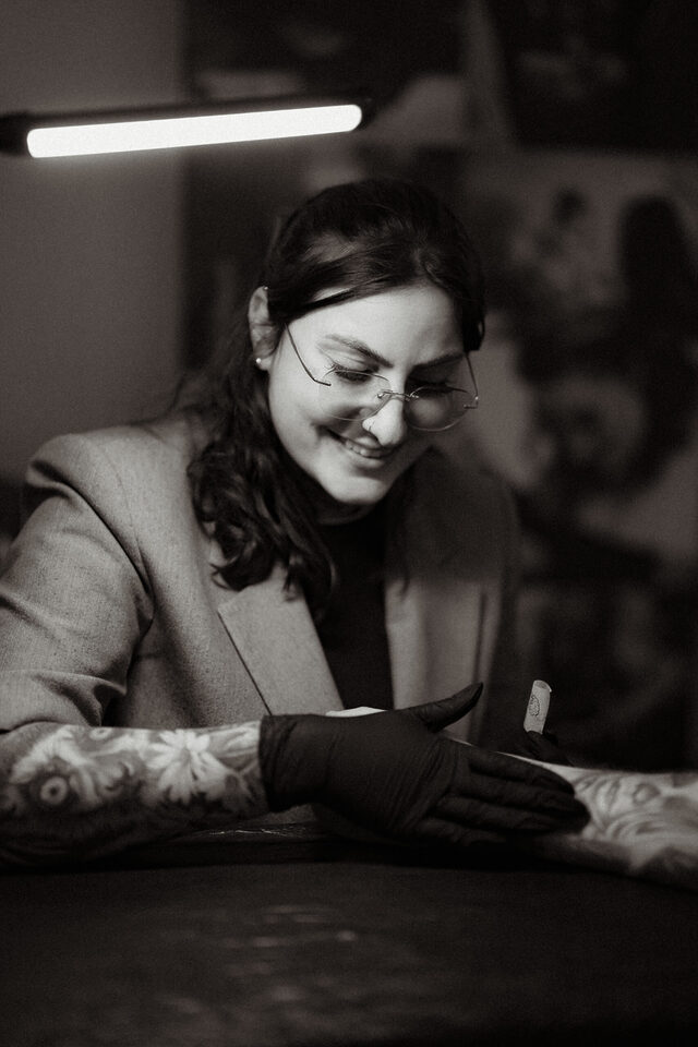 Dannii von ink moment lächelt während sie ein Tattoo auf den Unterarm eines Hochzeitsgastes überträgt.