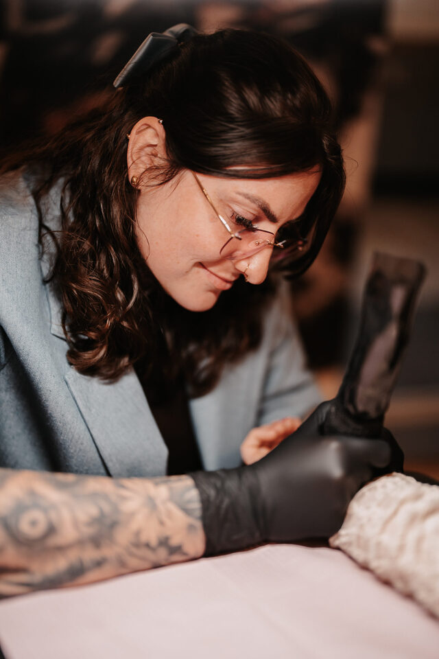 Tattooartist Dannii von ink moment sticht konzentriert ein Hochzeitstattoo bei einem Live-Tattoo-Event.