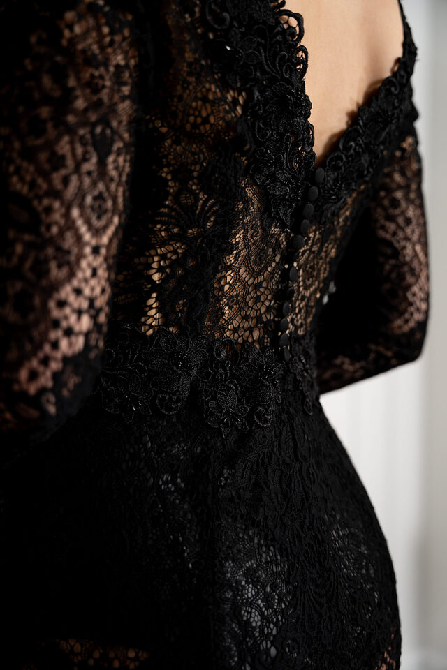 Detailaufnahme eines schwarzen Spitzenoutfits mit transparenten Partien und geschwungenem Ausschnitt