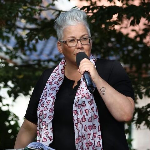 Tanja Rauth spricht bei einer freien Trauung im Freien in ein Mikrofon.